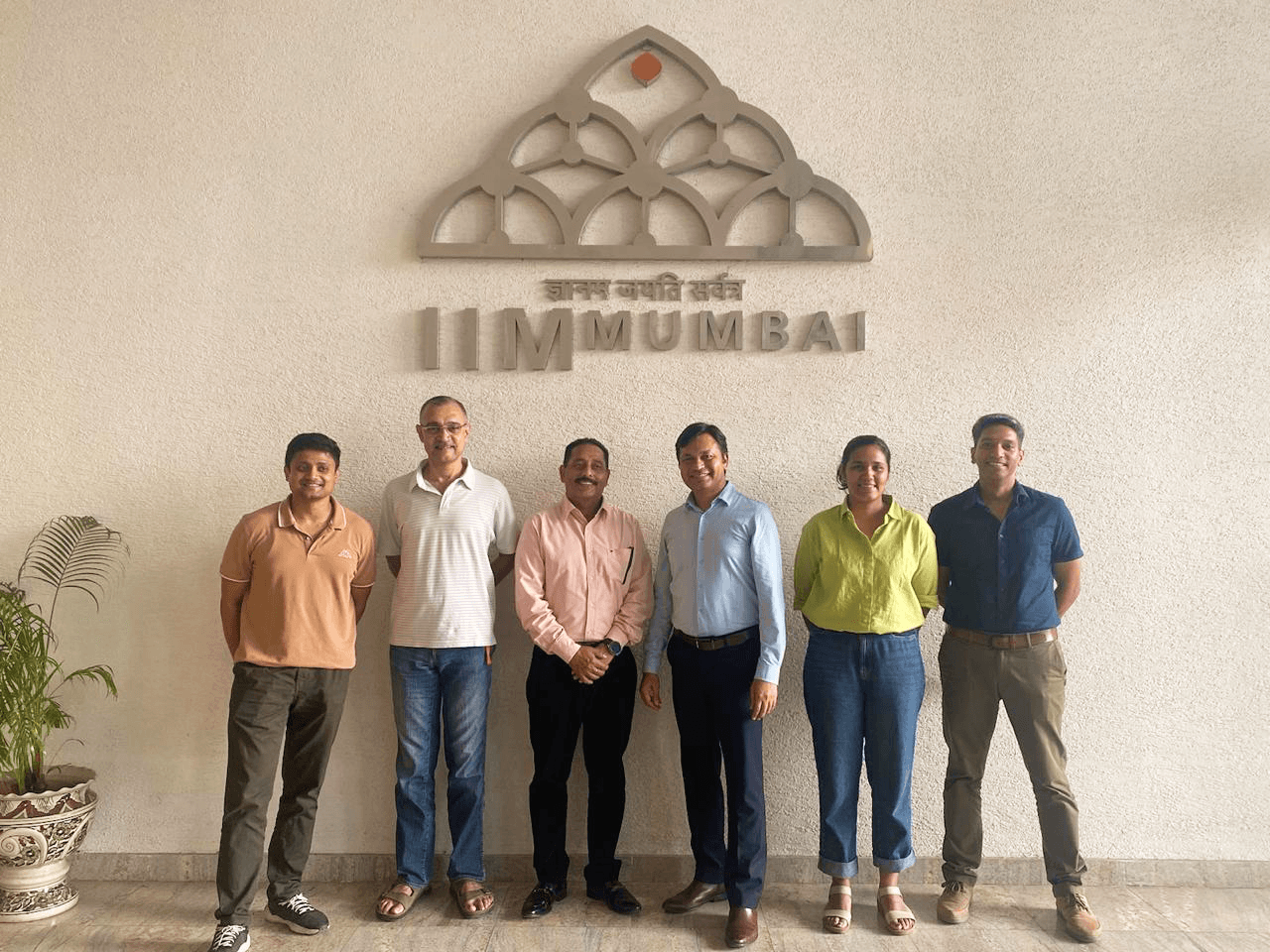 Professionals standing together in front of the IIM Mumbai emblem